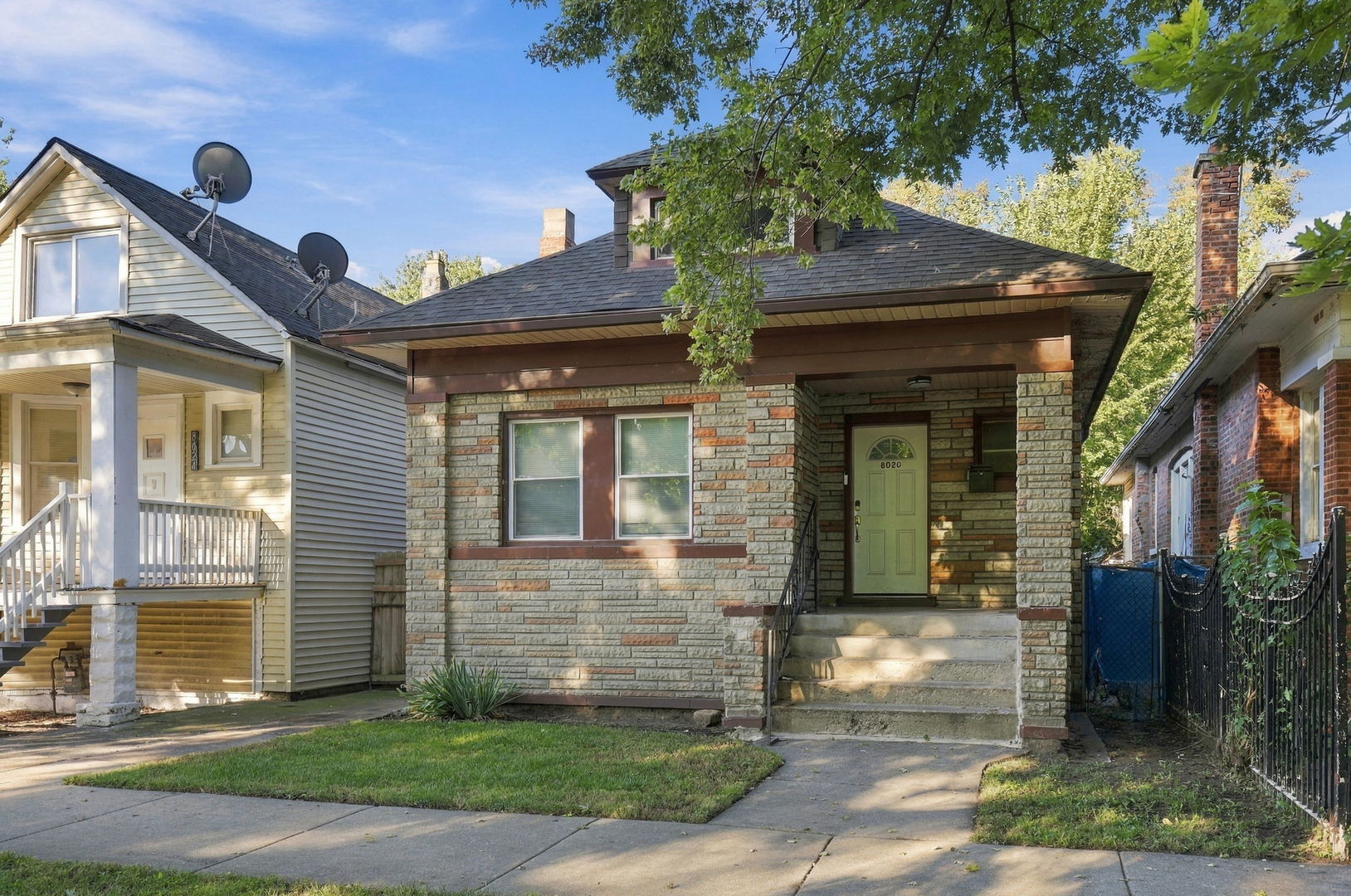 Stone-front Chicago home with a covered entry, front steps, and leafy shade.