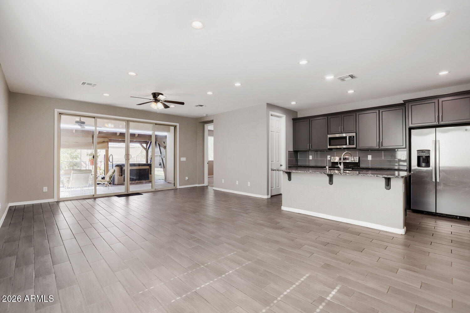 Open kitchen and living area with dark cabinets, a granite breakfast bar, and sliding doors to a patio.