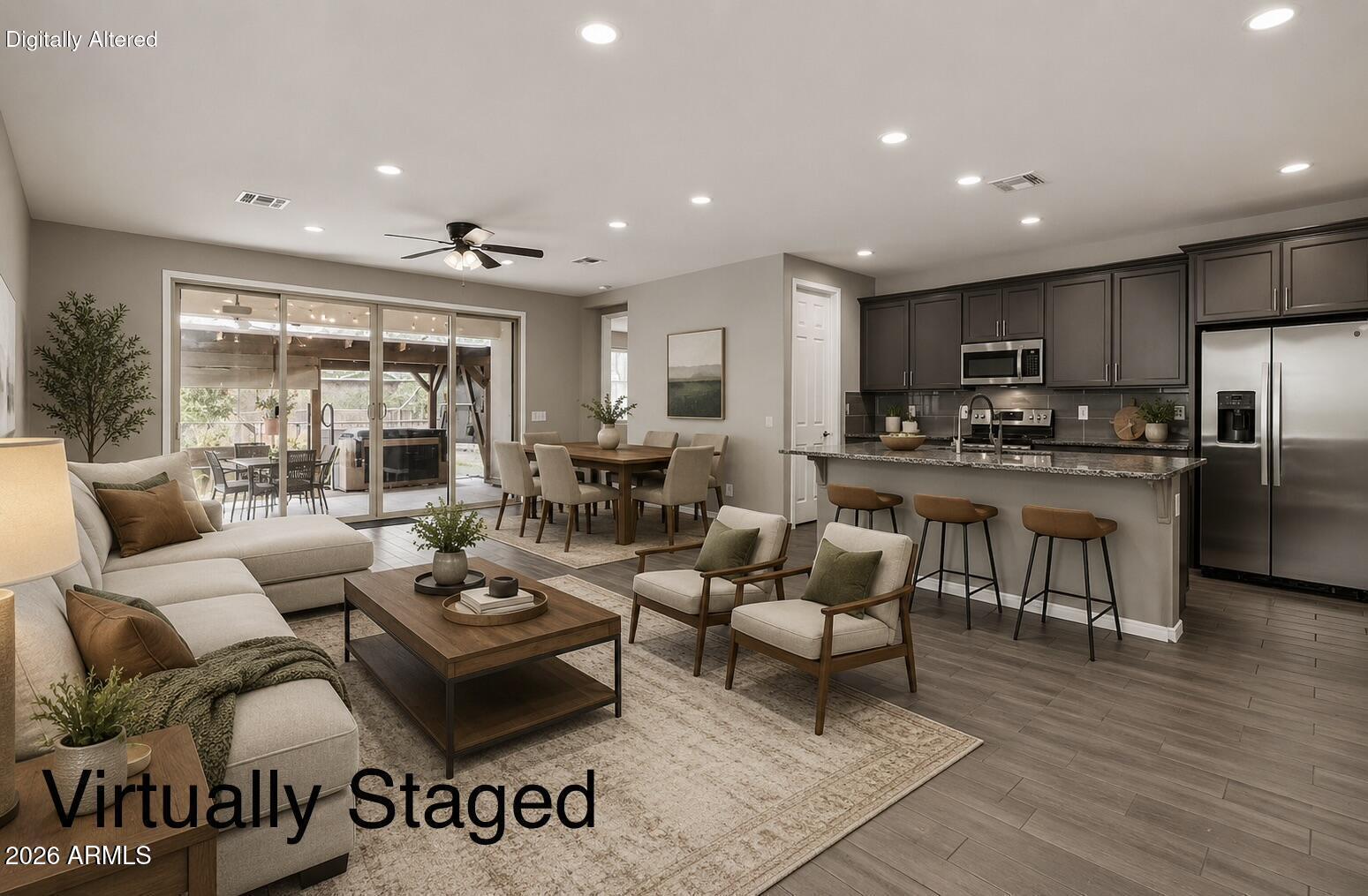 Open-plan living room, dining area, and kitchen with dark cabinetry and sliding doors to a covered patio.