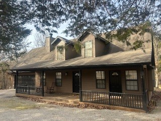 Brown wood-sided house with a covered front porch and gravel drive.