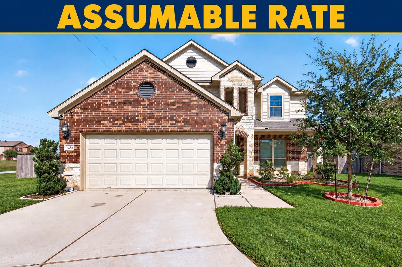 Two-story brick and stone house with a wide driveway and an “ASSUMABLE RATE” banner.