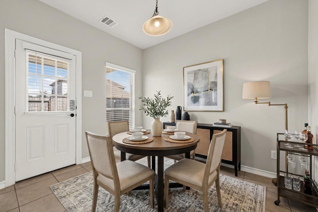 Dining room with a round table set for four beside a glass-paneled door and windows.