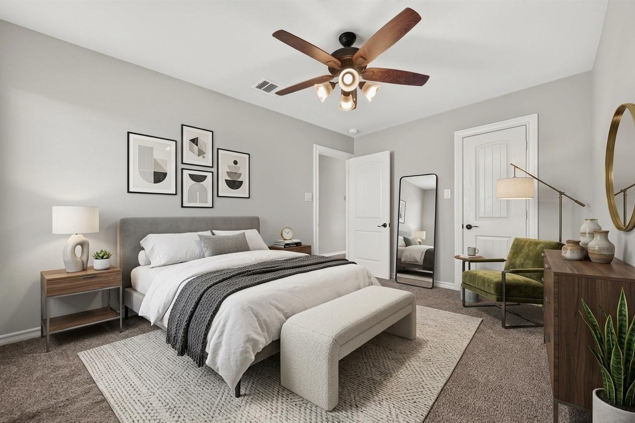 Staged bedroom with gray upholstered bed, white bedding, cream bench, geometric wall art, and green accent chair.