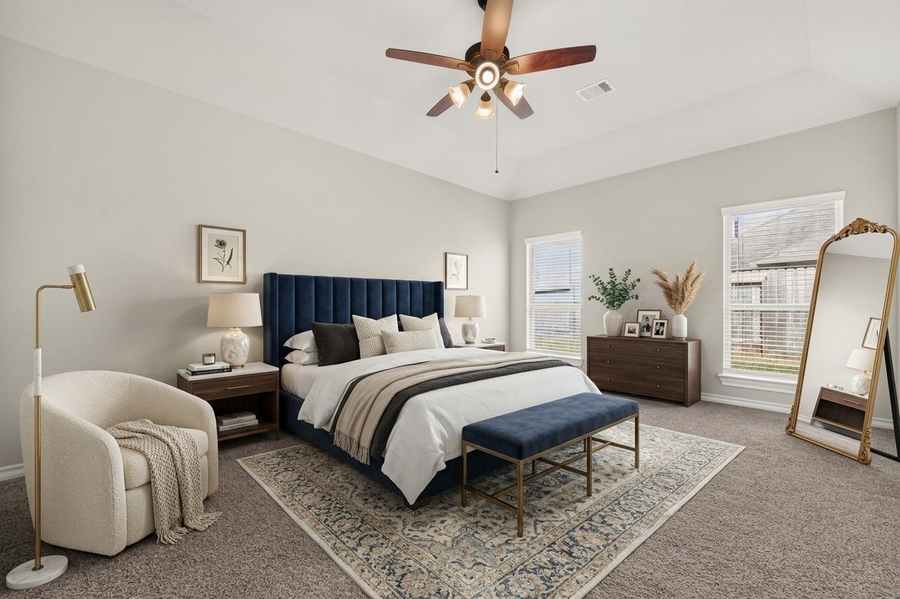 Bedroom with a navy upholstered bed, patterned rug, and cream accent chair.