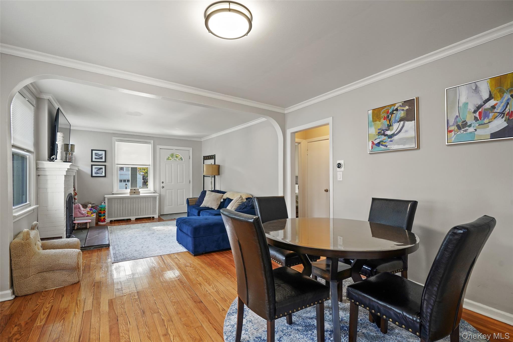 Living and dining room with hardwood floors, white brick fireplace, and blue sectional sofa.