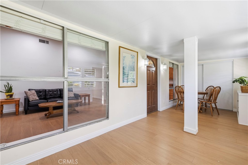 Dining area with a wooden table and chairs beside a glass-partitioned living room.
