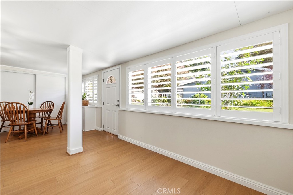 Dining area with plantation shutters, a wooden table, and light wood flooring.
