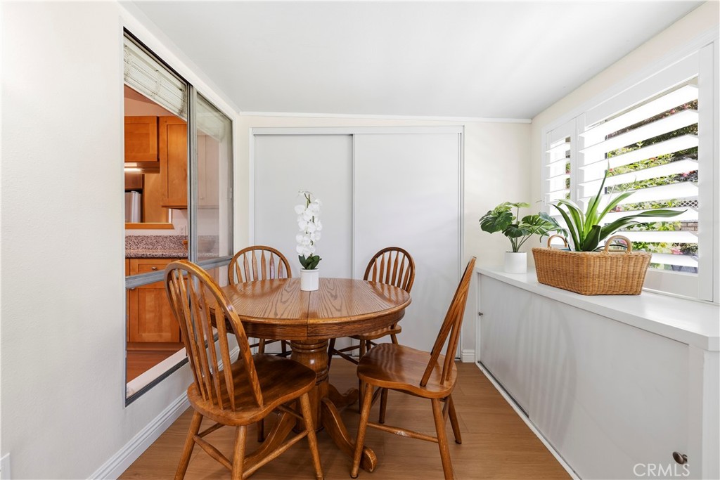 Dining nook with a round wooden table, spindle-back chairs, and white plantation shutters.
