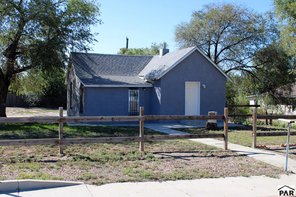 Gray single-story house with a wooden rail fence and walkway to the front door.