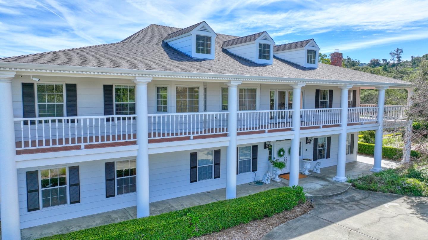 White two-story house with three roof dormers and a long, columned front porch.