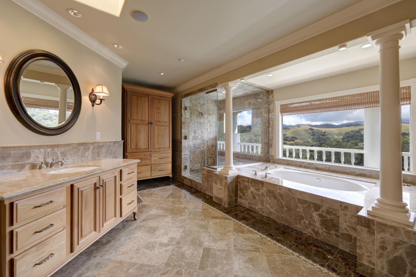 Marble bathroom with a built-in soaking tub and window overlooking rolling hills.