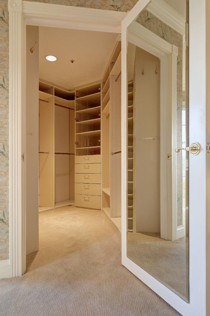 Walk-in closet with built-in shelving and drawers, viewed through an open mirrored door.