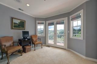 Furnished sitting room with a computer desk and French doors opening to a balcony.