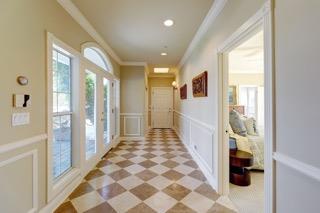 Entry hallway with checkerboard tile, white wainscoting, tall windows, and a glass-paneled door.