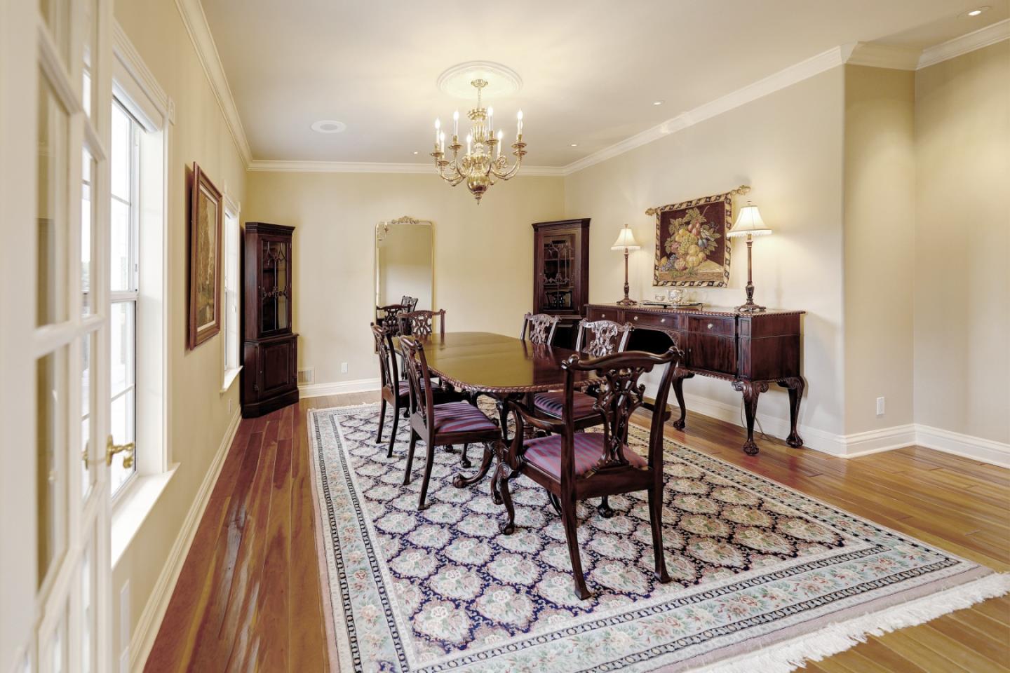 Furnished dining room with a carved wood table, chandelier, and large patterned rug.