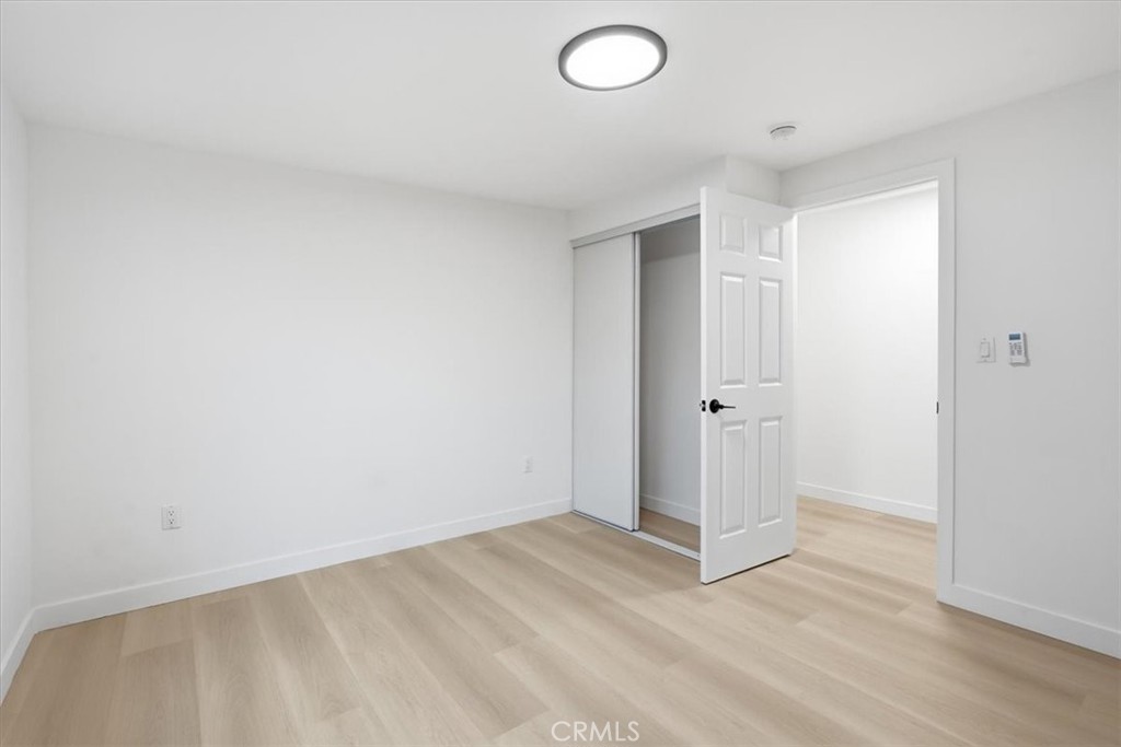 Empty bedroom with pale wood floors and an open doorway beside the closet.