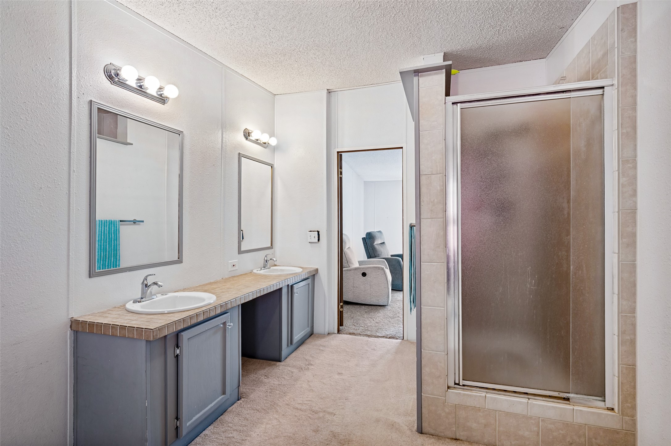 Bathroom with a double-sink vanity and tiled shower with sliding glass door.