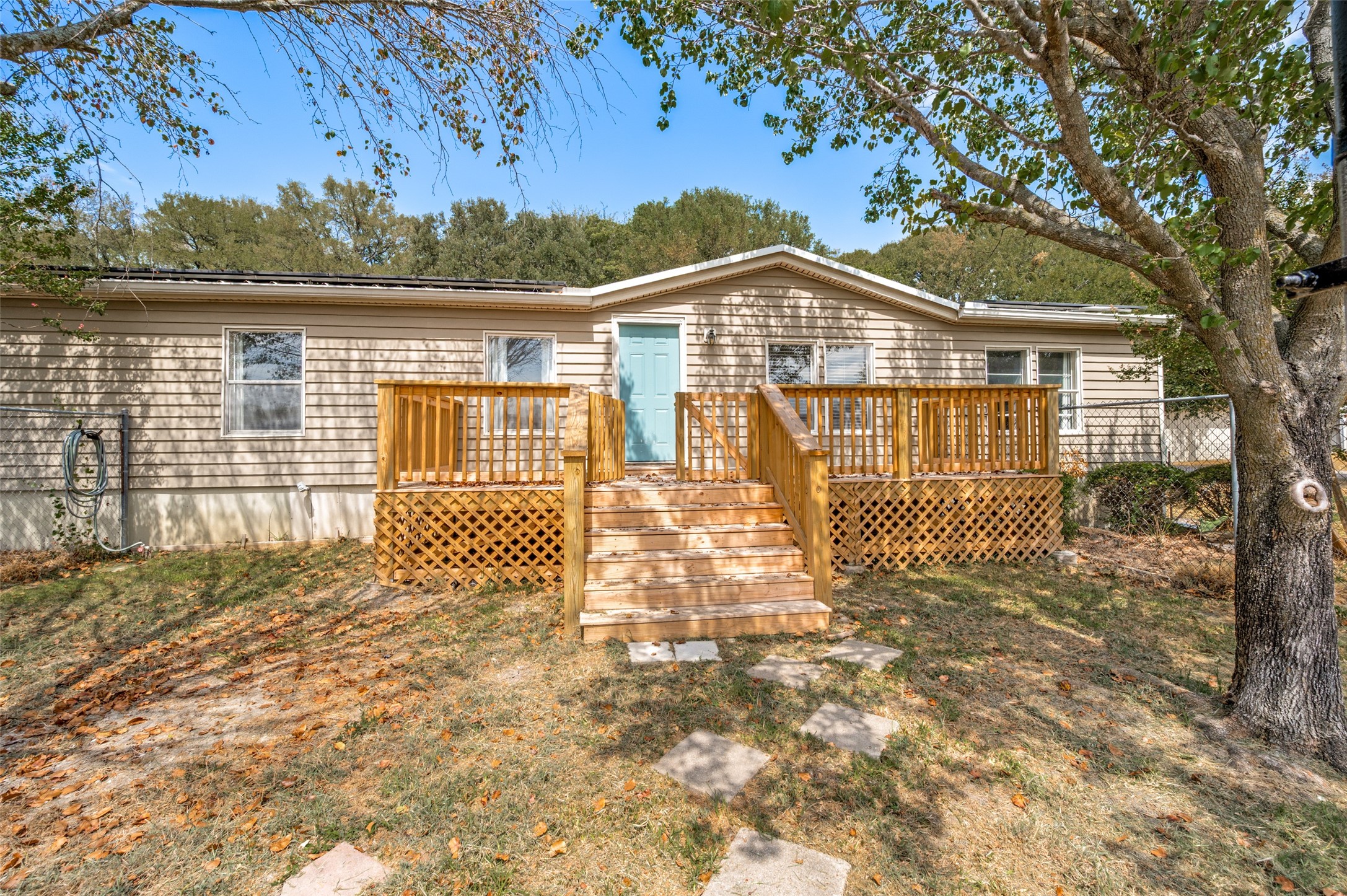 Home’s rear exterior with a raised wooden deck, central stairs, and light blue door.