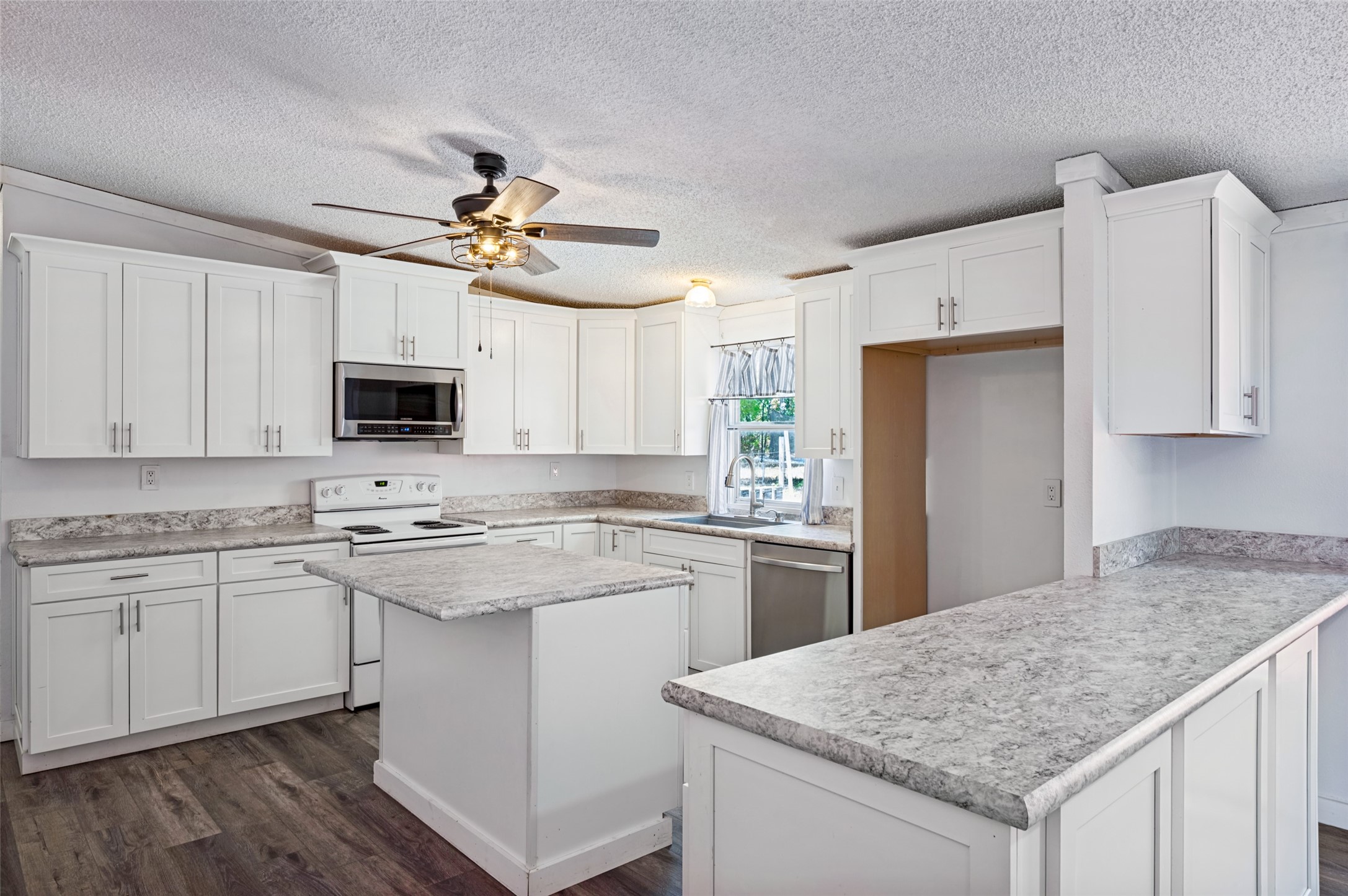 Kitchen with white cabinets, gray countertops, a central island, and a wide peninsula.