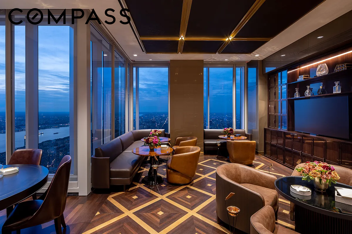 High-rise living room with floor-to-ceiling windows, city and water views, and a geometric wood floor.