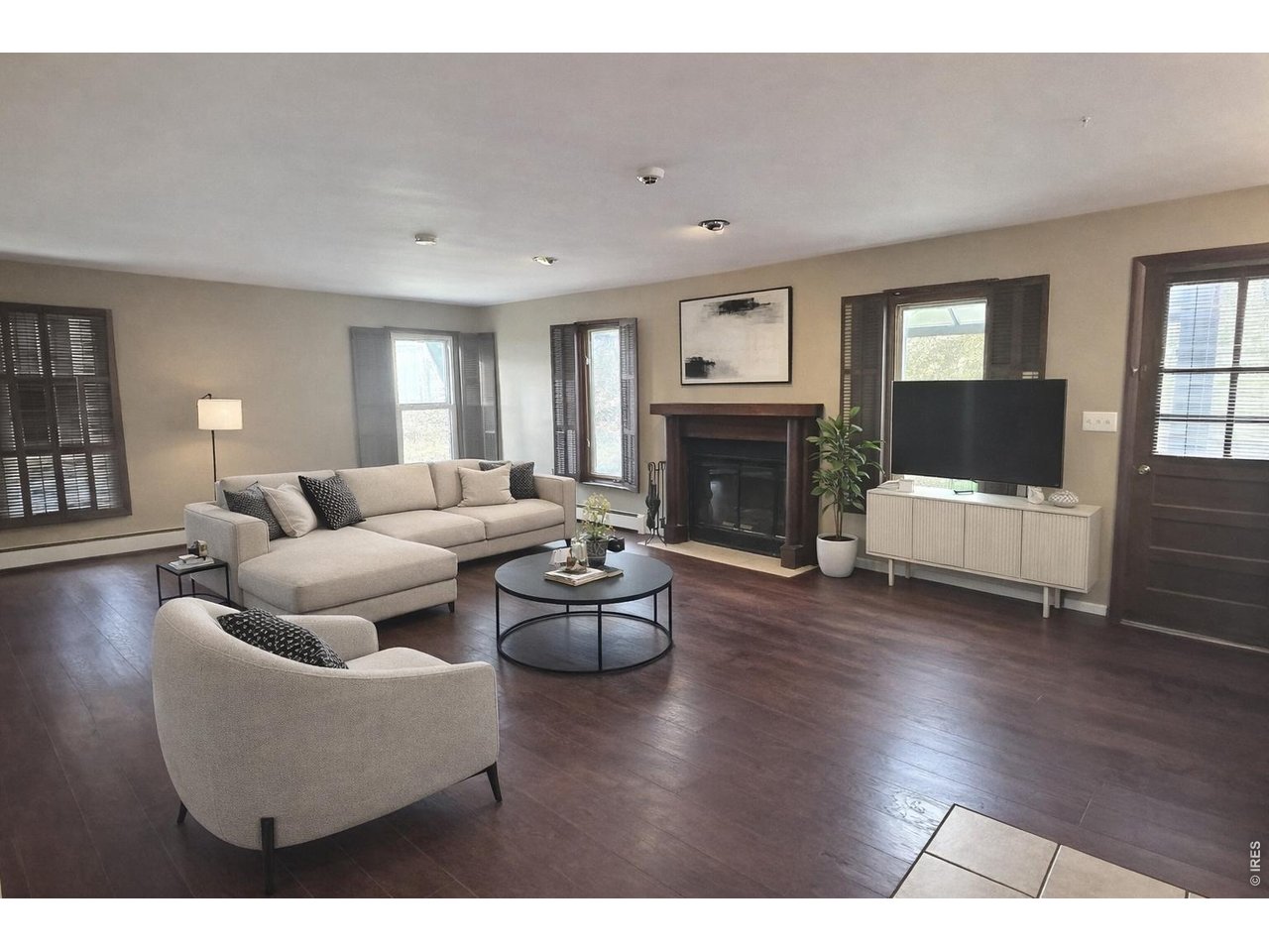 Living room with a light sectional, dark wood floors, and a fireplace with a wood mantel.