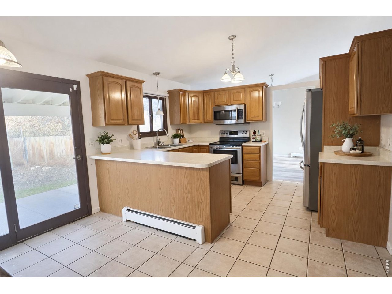 Kitchen with wood cabinets, a central peninsula, stainless steel appliances, and a sliding glass patio door.
