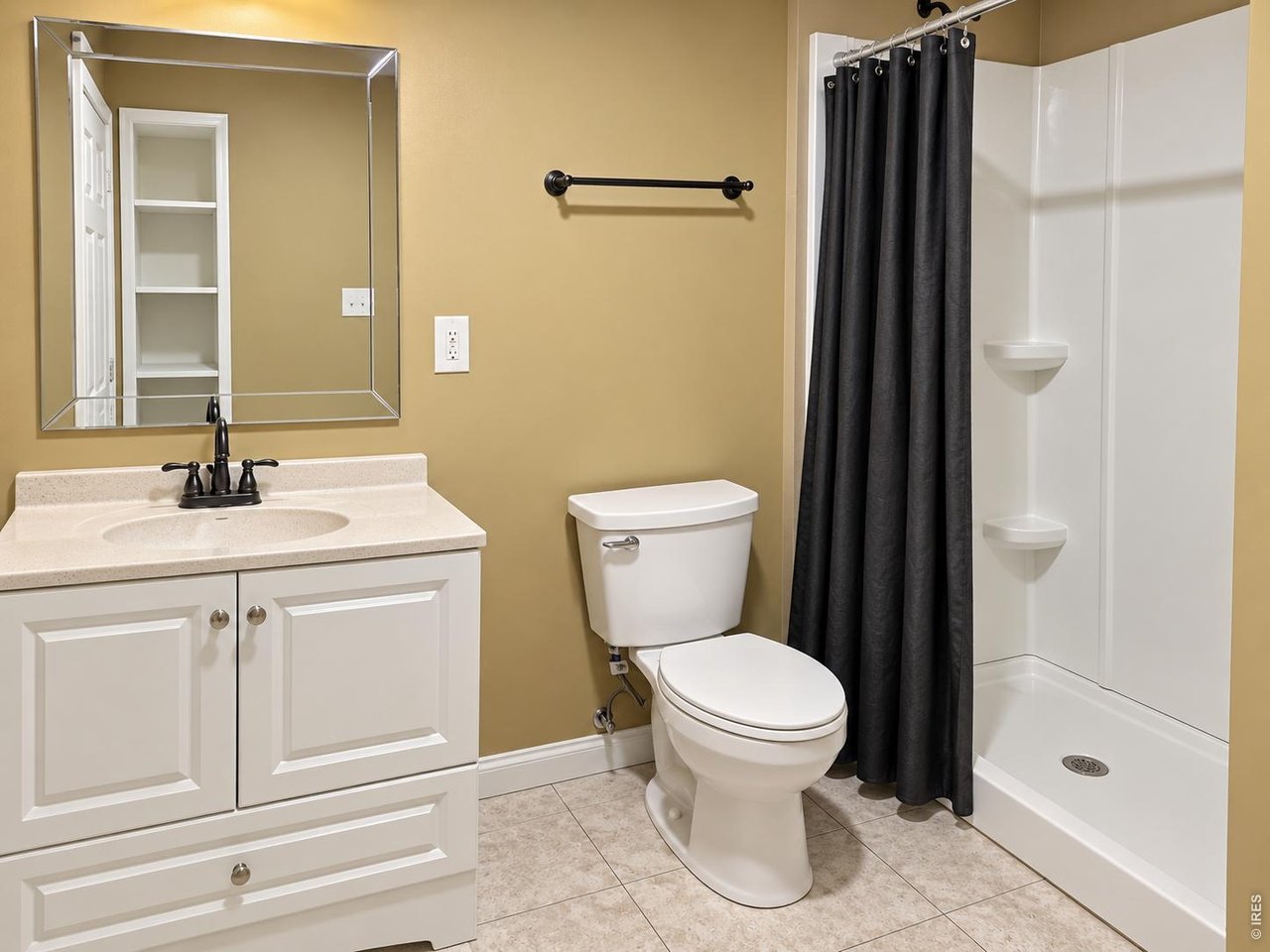 Bathroom with a white vanity, toilet, and shower behind a black curtain.