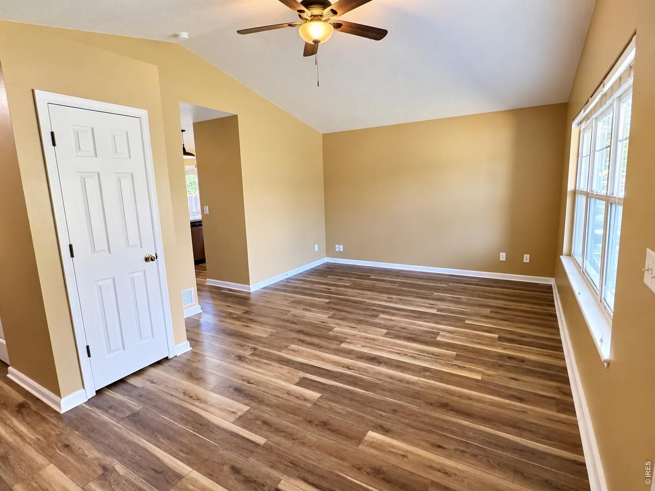 Empty room with wood-look floors, a ceiling fan, and large windows.