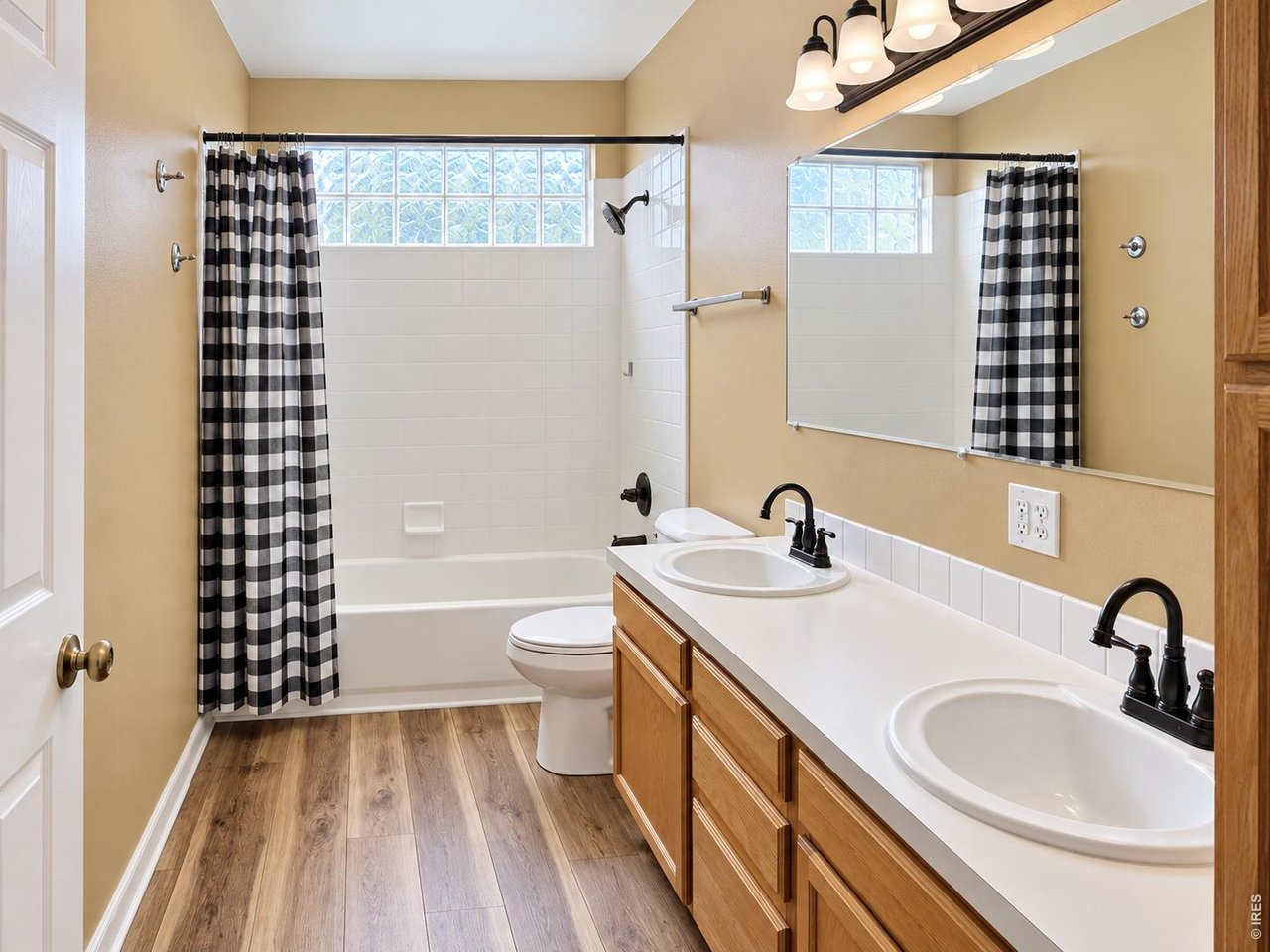 Bathroom with a tub, checkered shower curtains, and a double-sink wood vanity.