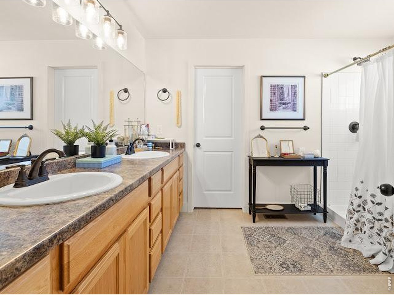 Bathroom with a double-sink wood vanity and a shower with a patterned curtain.