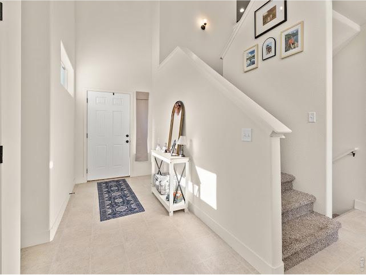 Bright entryway with a white front door, console table, and carpeted staircase.