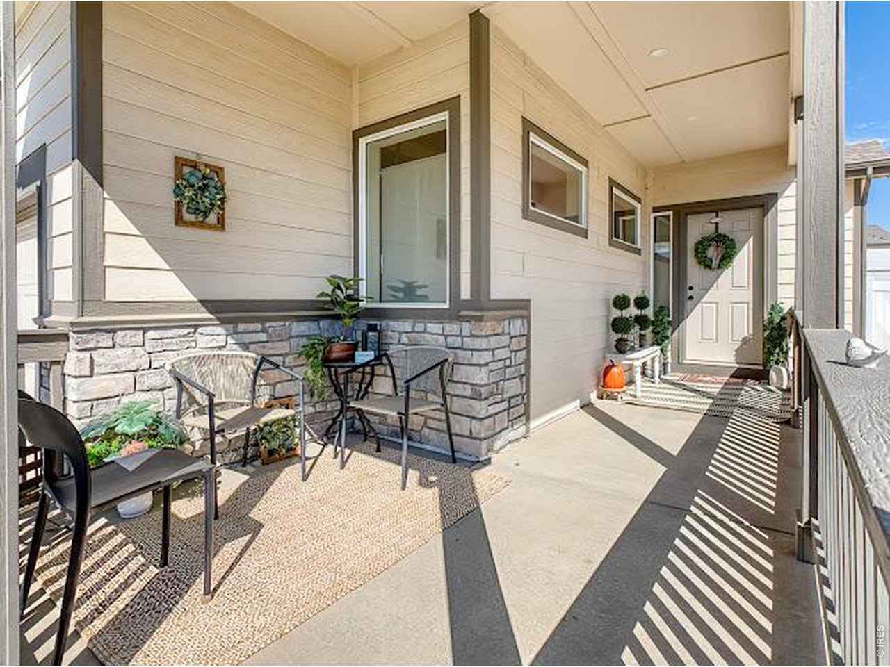 Covered front porch with seating, stone half walls, and a wreath on the front door.