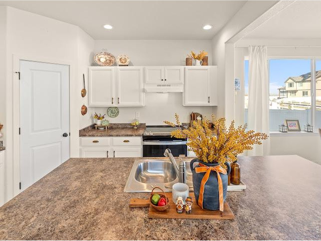 Kitchen with white cabinets, granite counters, and a decorated island with a stainless-steel sink.