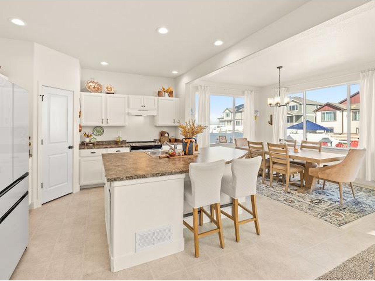 Open-plan kitchen and dining area with a granite island and large windows.