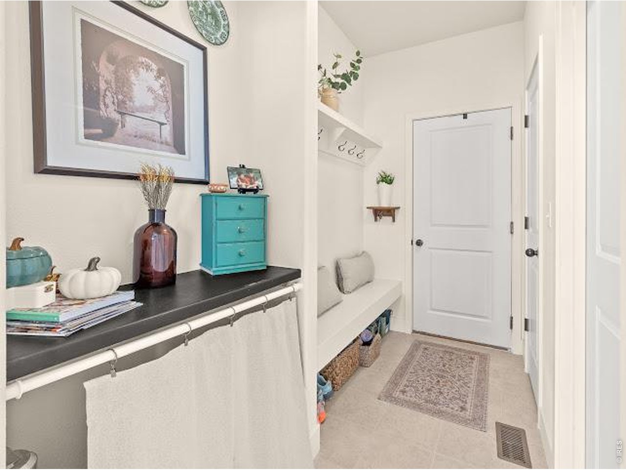 Entryway with a built-in bench, coat hooks, and a colorful console shelf.