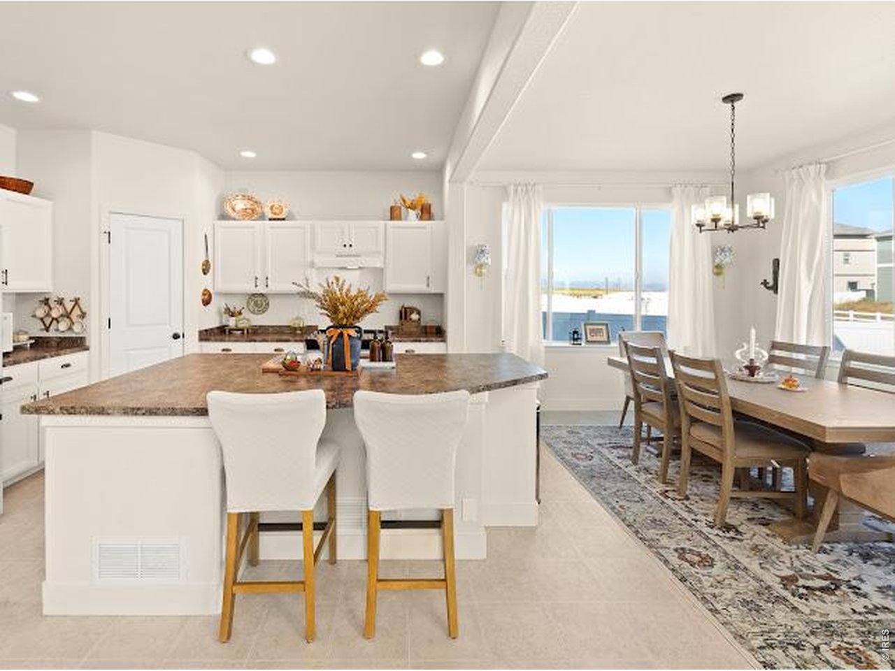 Open-plan kitchen and dining area with a large island, white cabinetry, and a long wooden table.