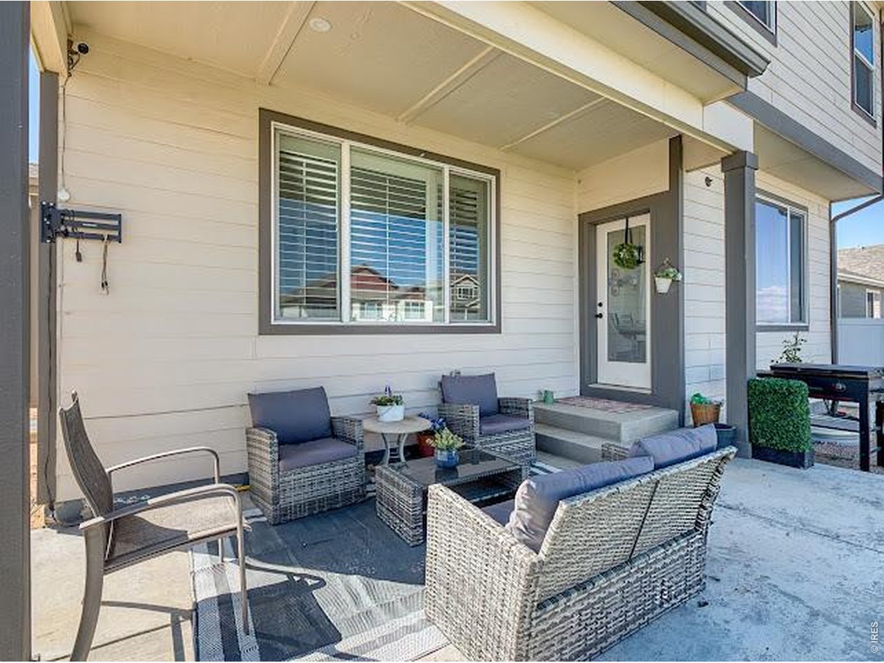Covered patio with wicker seating, an outdoor rug, and a glass-paneled door.
