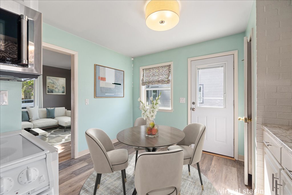 Dining area with a round table and four chairs, mint-green walls, and a white exterior door.
