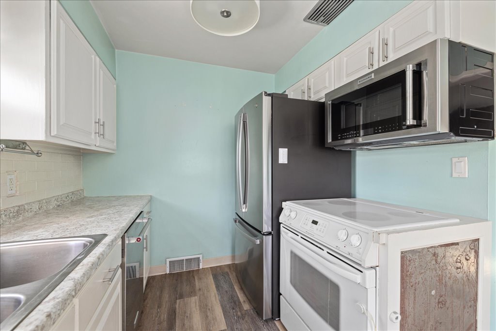 Compact aqua kitchen with white cabinets, a stainless-steel refrigerator, and a white oven.