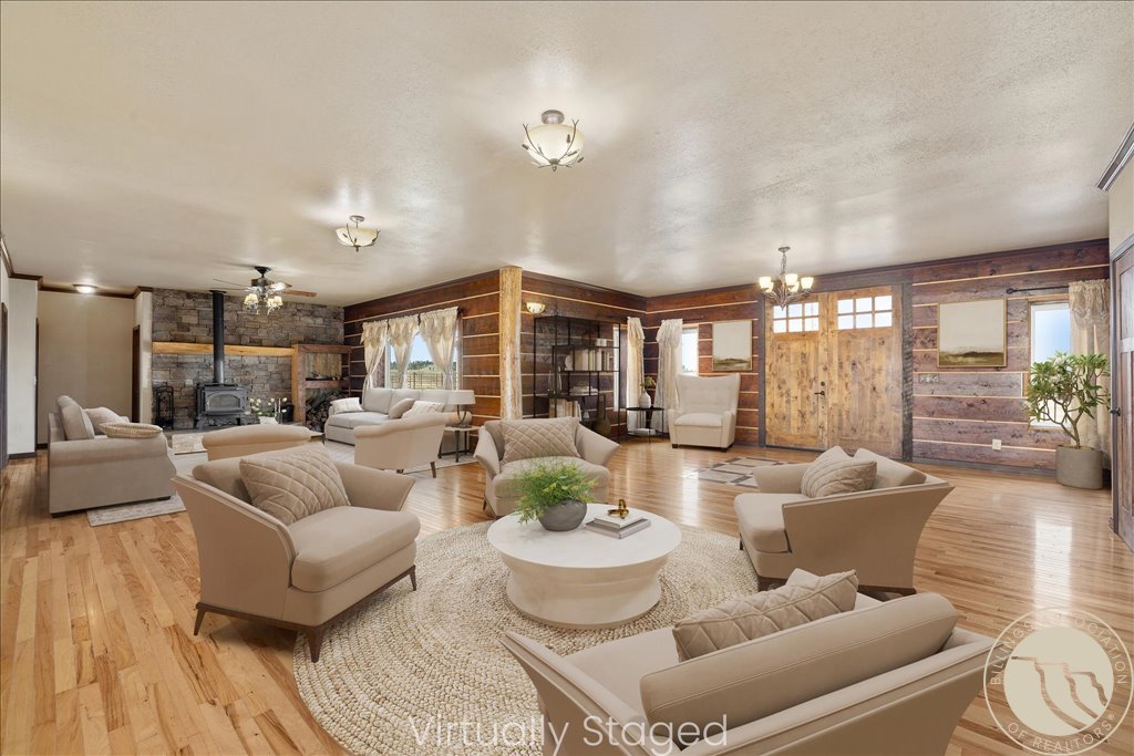 Living room with a stone fireplace, dark wood-paneled walls, and cream seating.