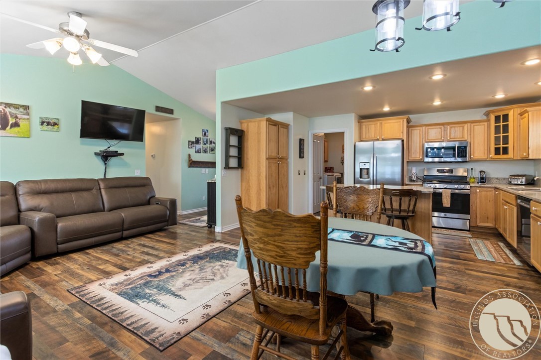 Open-plan living and kitchen area with mint-green walls, wood cabinets, and a brown leather sofa.
