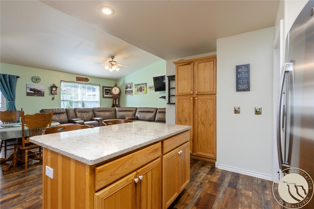 Kitchen with a large wood island and stone countertop, opening to a dining area and living room.
