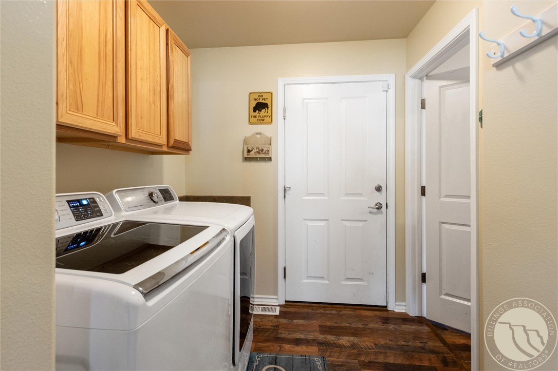 Laundry room with wood cabinets, washer and dryer, and a white entry door.