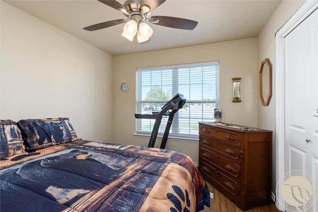 Bedroom with a patterned bedspread, treadmill by the window, and carved wooden dresser.