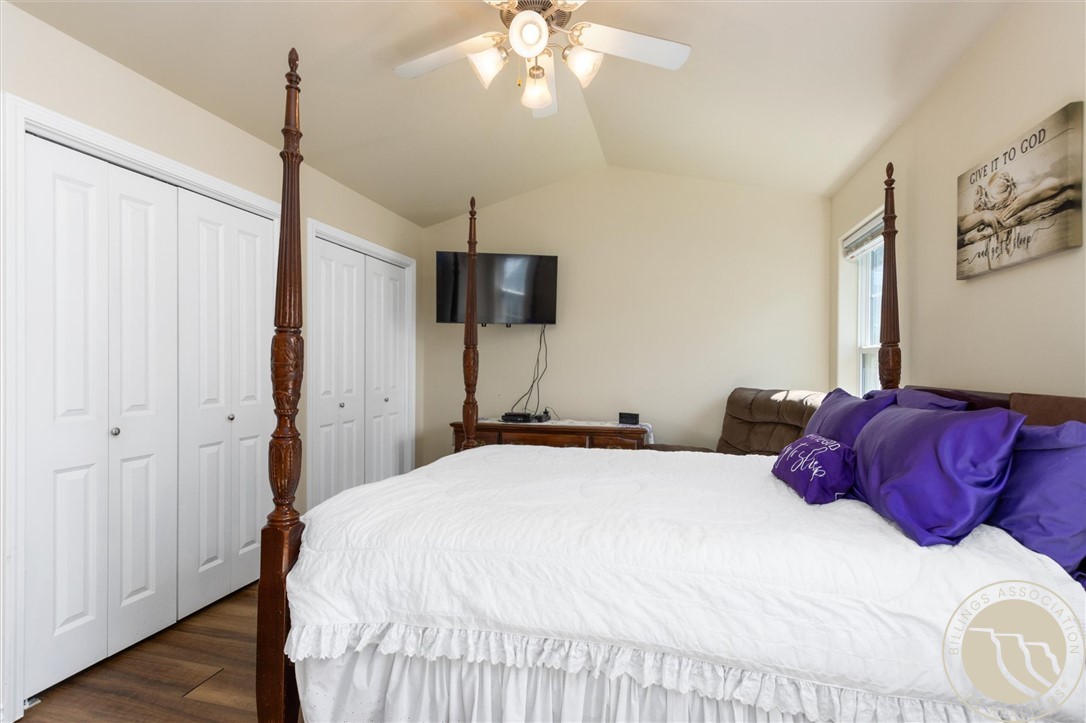 Bedroom with a white four-poster bed, purple pillows, and double closet doors.