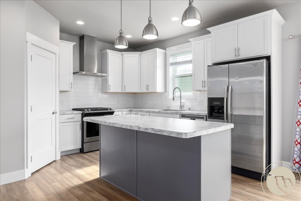 Modern kitchen with a dark gray island, white cabinets, and stainless steel appliances.