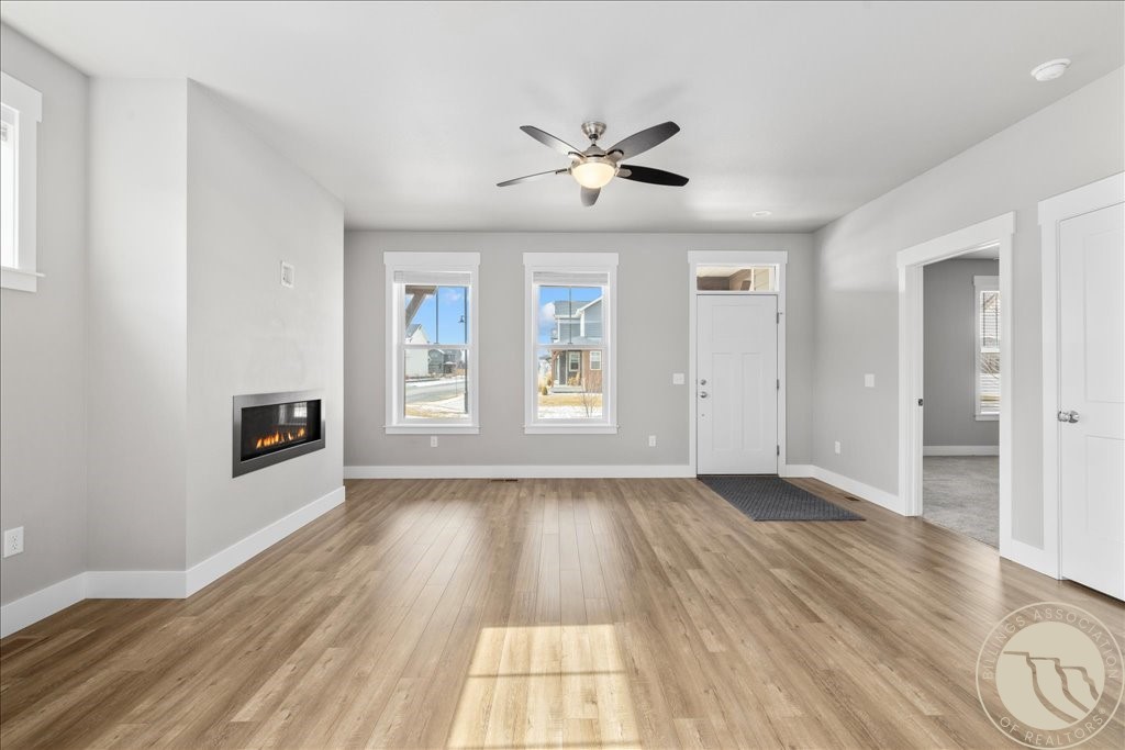 Empty living room with wood-look flooring, a built-in fireplace, and two front windows.