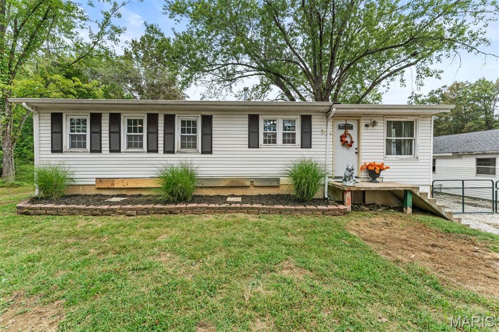 Single-story white ranch home with dark shutters, a small front porch, and a broad lawn.