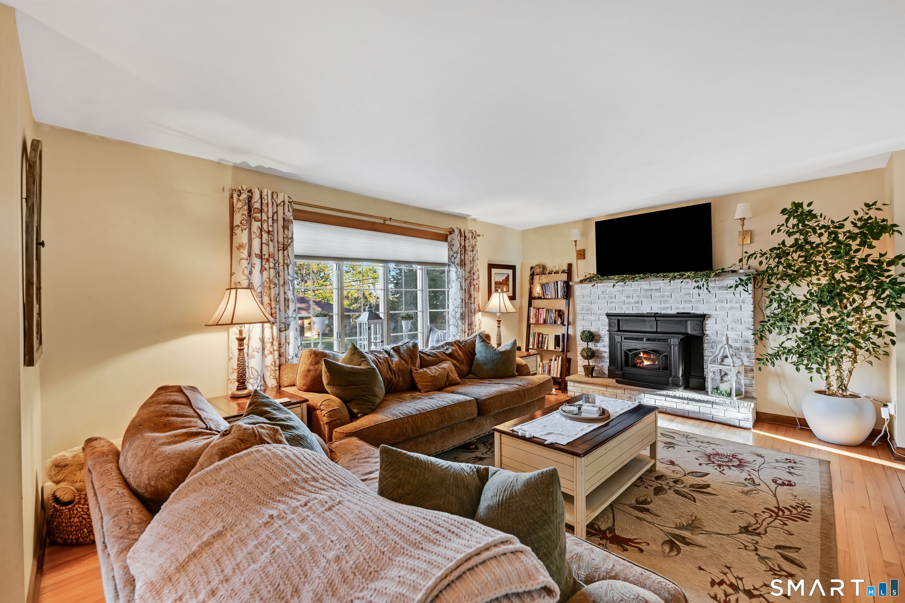 Furnished living room with a lit fireplace, two sofas, and a large window.