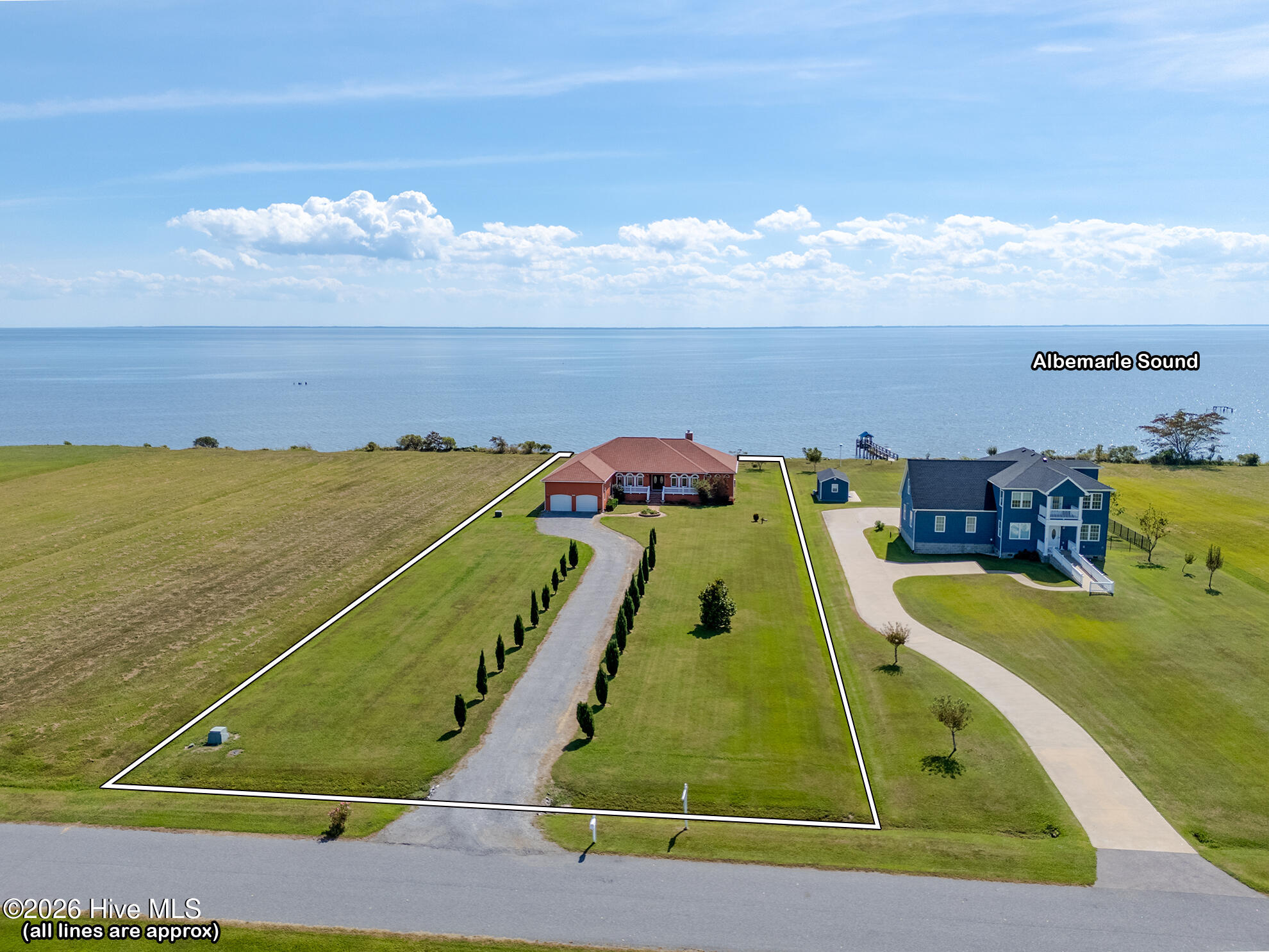 Aerial view of a brick waterfront home, with its outlined lawn and driveway beside Albemarle Sound.